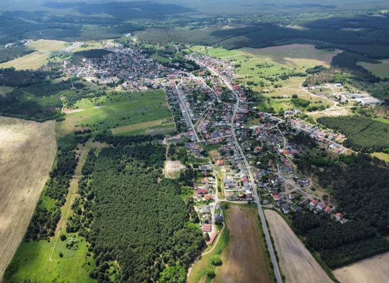 Aerial view of agricultural and forest land in Studienka with visible buildings and forests.