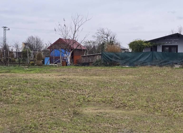 Grassy plot with wooden and brick structures on Recreational lands in Drahovce.
