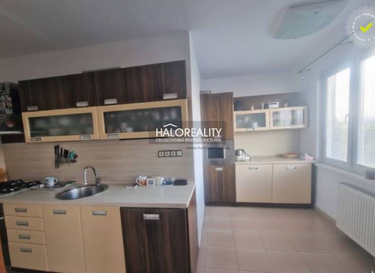 A kitchen in a 3-room apartment with dark cabinets and tiles, bright environment.