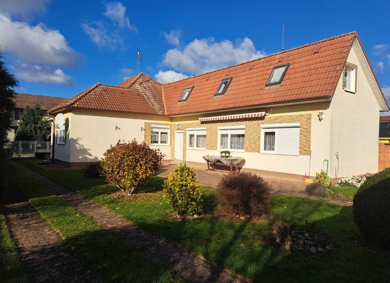 A family house on Bernolákova Street in Vráble, surrounded by a green garden and a blue sky.