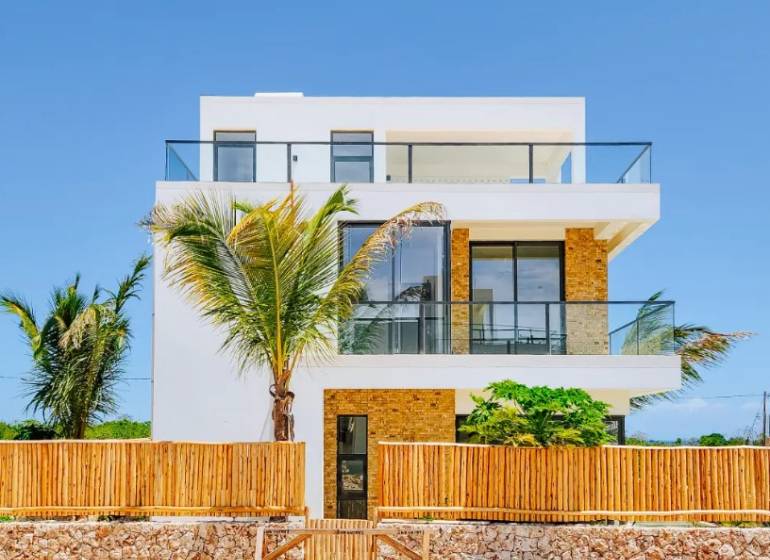 A villa in Fumba Town with glass balconies and exotic palm trees in the foreground.