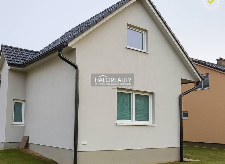 A family house in Kľačno with a white facade and a sloped roof on a well-maintained lawn.