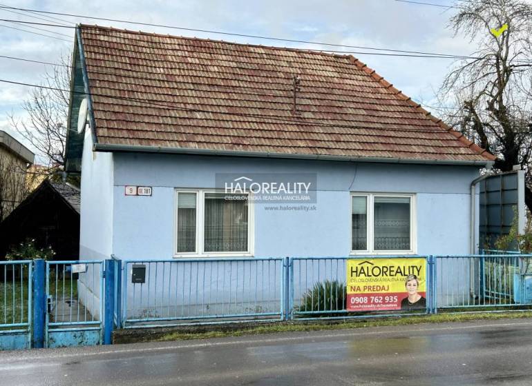 A single-story family house in Prievidza, blue facades, sloped roof, metal fence.