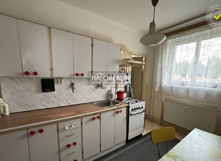 A kitchen in a 3-room apartment with white cabinets and a kitchen counter with a wood decor.