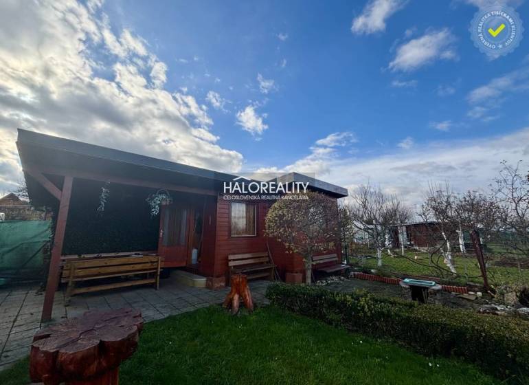 A wooden cottage in the gardens of Spišská Nová Ves with benches and a flower bed.
