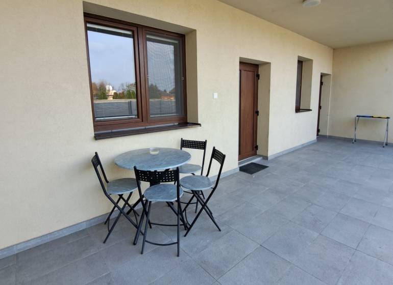 A terrace with seating in a 4-room apartment with a tiled floor and light walls.