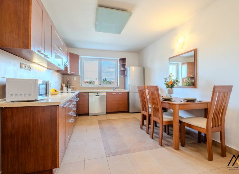 A kitchen in a 2-room apartment with a wooden decor and a dining table.