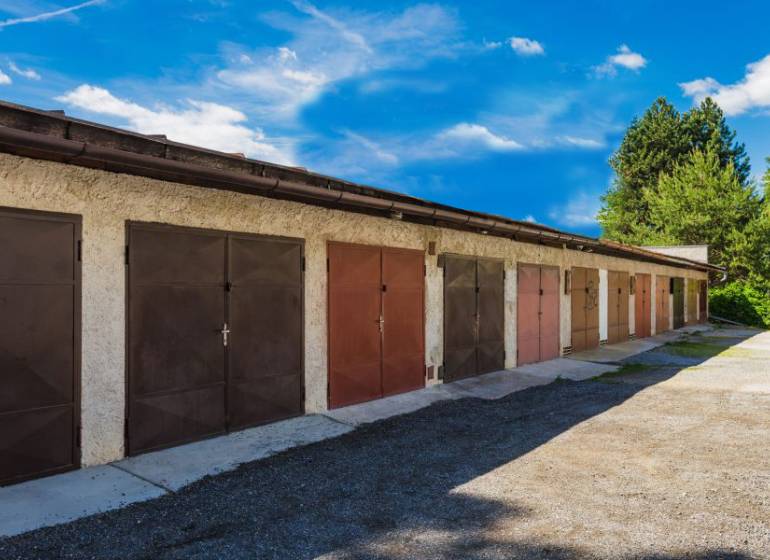 In a row, on Pálovická Street, stand garages with metal doors.