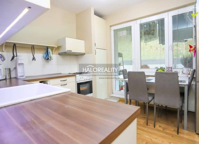 A kitchen in a 2-room apartment with a wood-patterned floor, a dining table, and appliances.