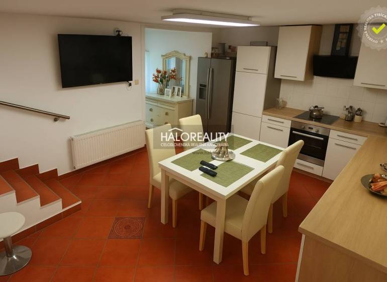 A kitchen in a family house with a tiled floor, a dining table, and a kitchen unit.