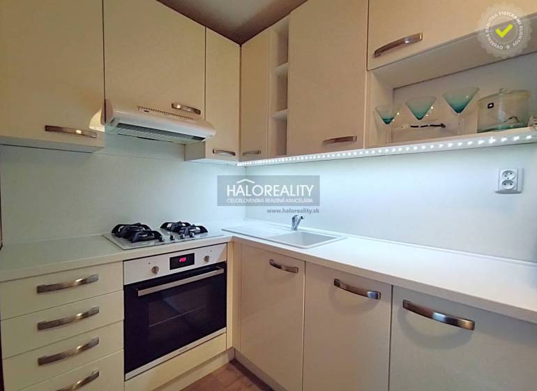 A kitchen in a 2-room apartment with white cabinets, a gas stove, and storage space.