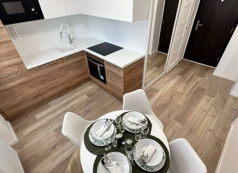 A kitchen in a 2-room apartment with a wood-patterned floor and a dining table.