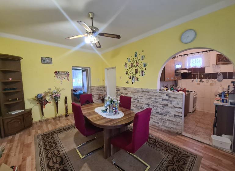 Dining room in a family house with a round table, chairs, and a wooden decor floor.
