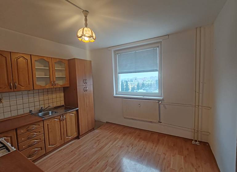 A kitchen with a wooden floor decor in a 3-room apartment with white walls and classic cabinets.