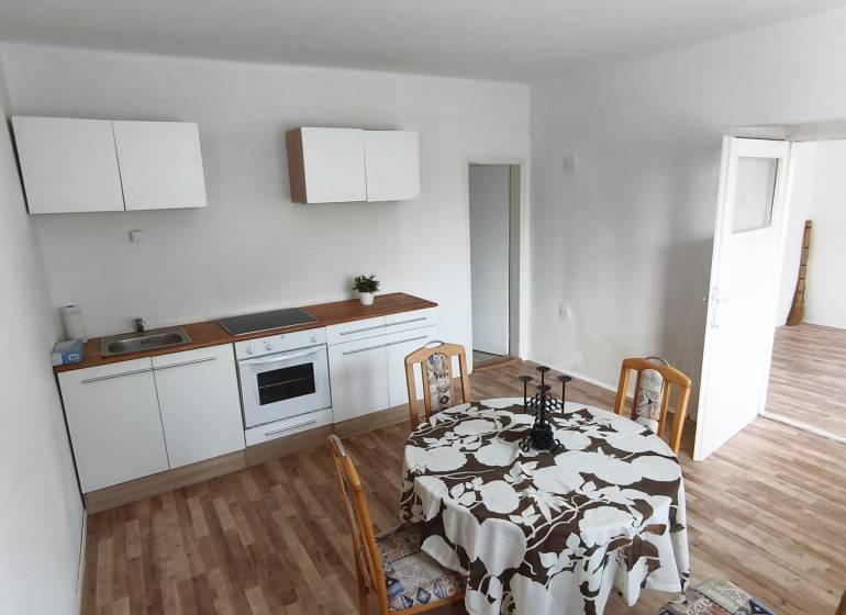 Kitchen and dining area with wood-patterned flooring in a family house.