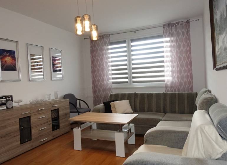 A bright living room with a corner sofa, a coffee table, and a sideboard in a three-room apartment.