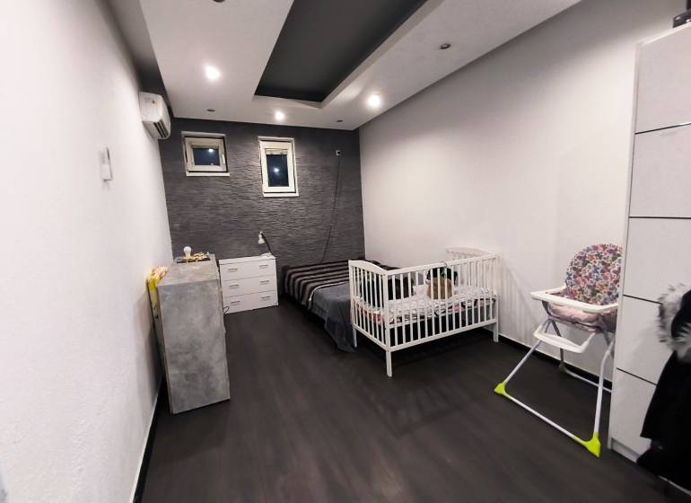 Children's room in a family house with a wooden decor floor and a wall with stone cladding.