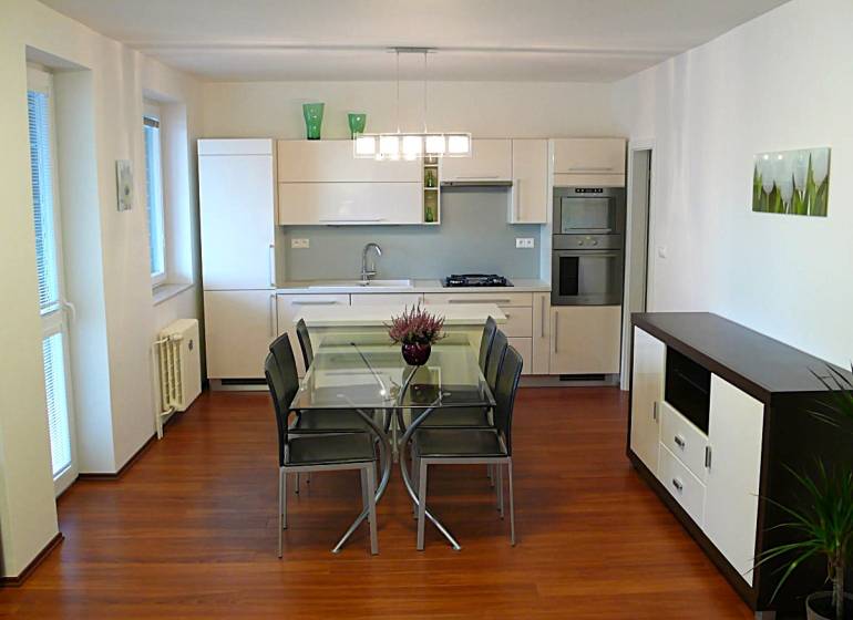The kitchen of a 4-room apartment with a dining table and a wooden decor floor.