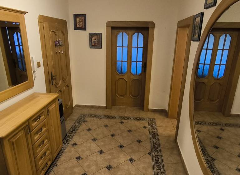 A hallway in a 3-room apartment with a mirror, tiles, and wooden furniture.