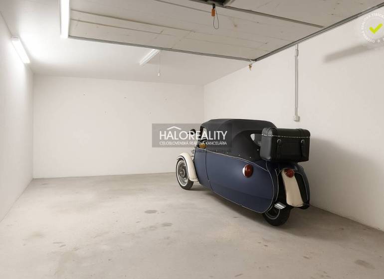 A garage in Borčice with a parked retro vehicle, smooth concrete floor, white walls.