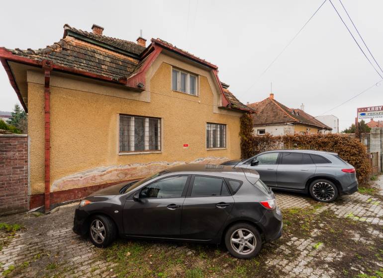 A family house on Partizánska Street in Bánovce nad Bebravou with two cars parked in front of it.