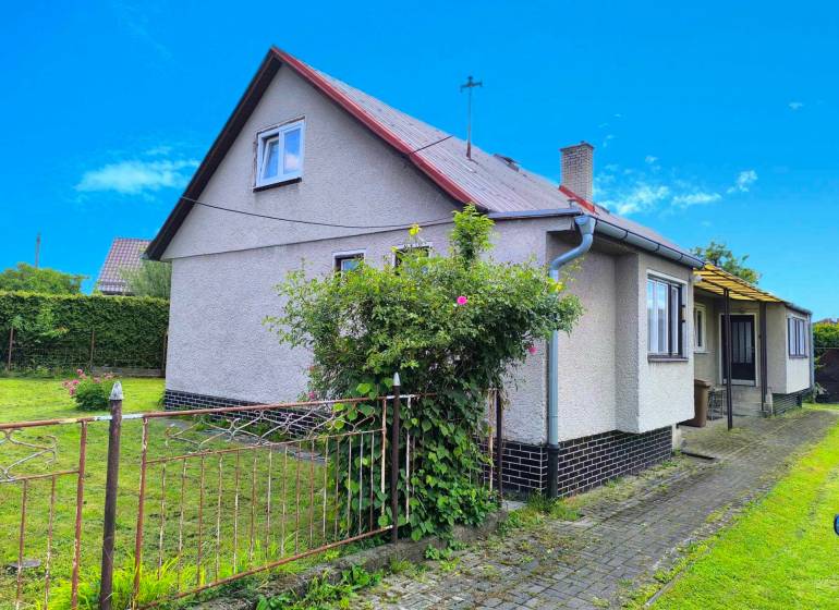A family house in Nováky with a lawn and garden, surrounded by a fence and plants.