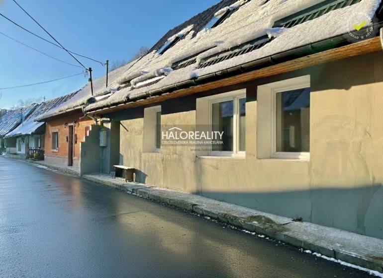A family house in Hronec with a snow-covered roof and a wet asphalt road.