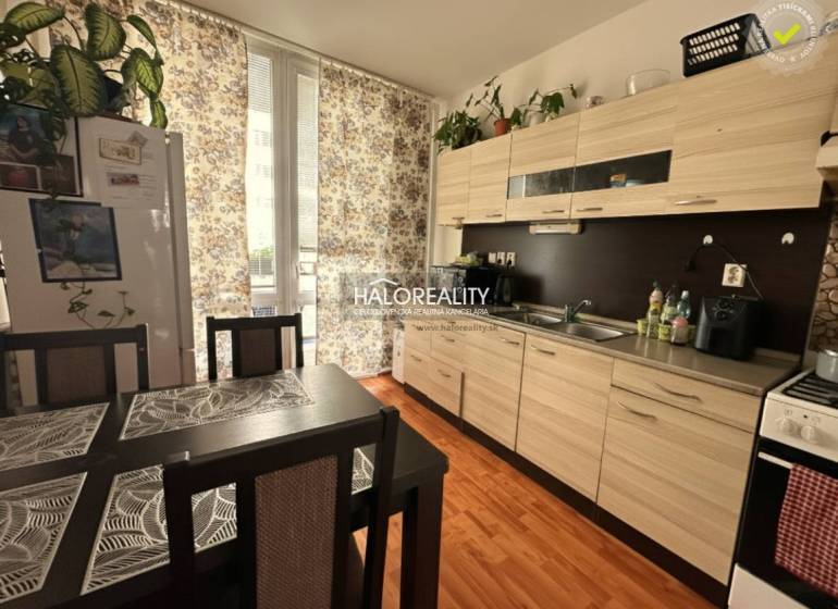 The kitchen in a 3-room apartment with a wooden decor floor, a dining table, and curtains.