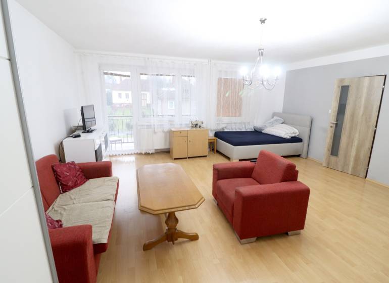 Living room in a family house with a sofa, table, and bed. Floor with wood decor.