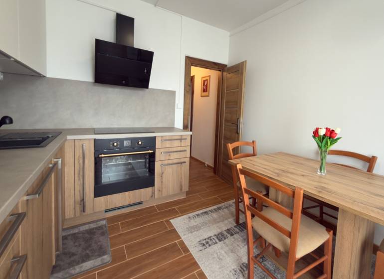 A kitchen in a 3-room apartment with a wooden decor, a dining table, and a kitchen unit.