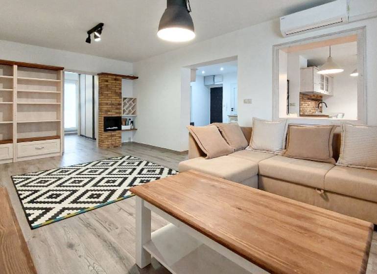 A living room in a three-room apartment with a wooden decor floor and comfortable seating.
