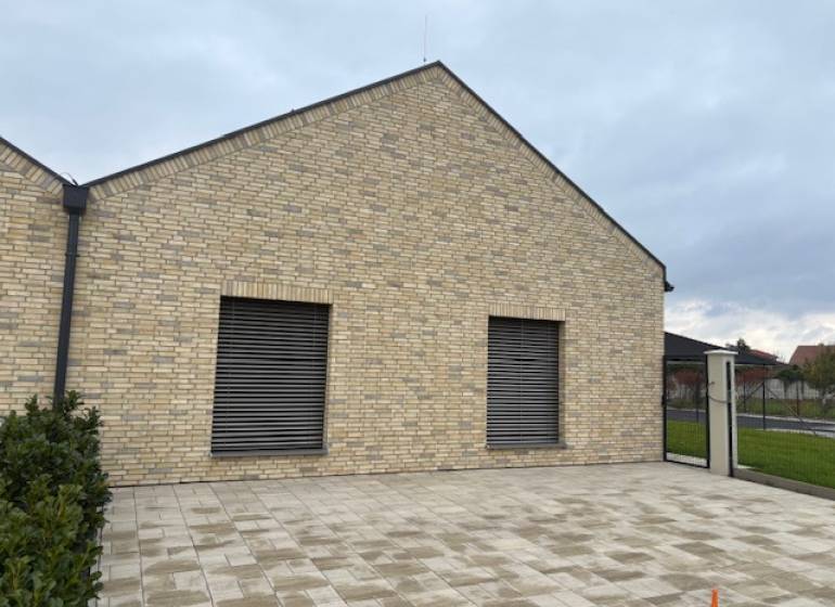 A family house on Fialkova Street in Tomášov with a brick facade and a paved courtyard.