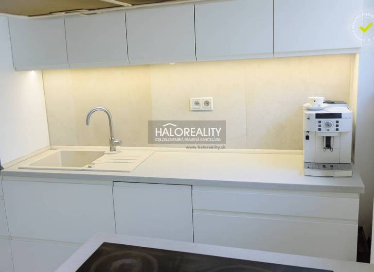 A kitchen with white cabinets and a coffee maker in a 3-room apartment.