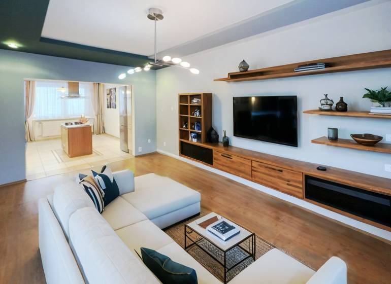 Living room in a 4-room apartment with a wooden decor floor, television, and sofa.
