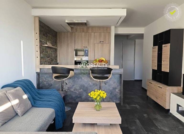 Living room in a two-room apartment with an open kitchen and a wooden decor floor.