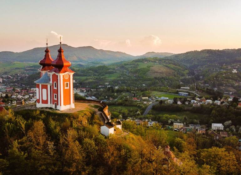 Calvary on the hill with a panorama of Banská Štiavnica, surrounded by agricultural and forest lands.