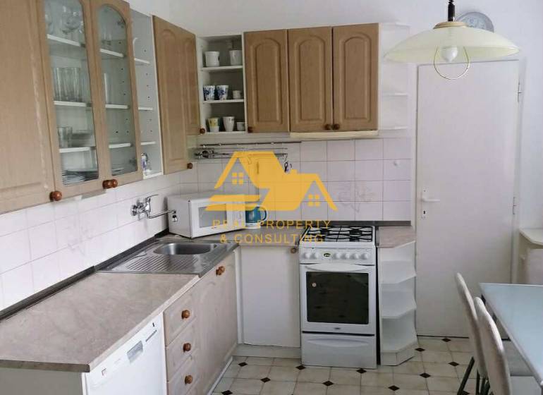 A kitchen with white cabinets, a gas stove, and a tiled floor in a three-room apartment.