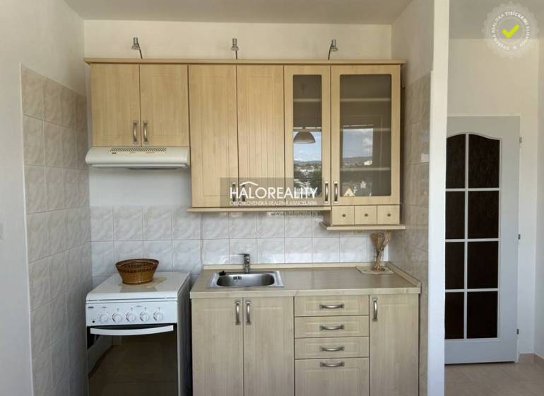 A kitchen in a studio apartment with a wooden decor and white tiles.