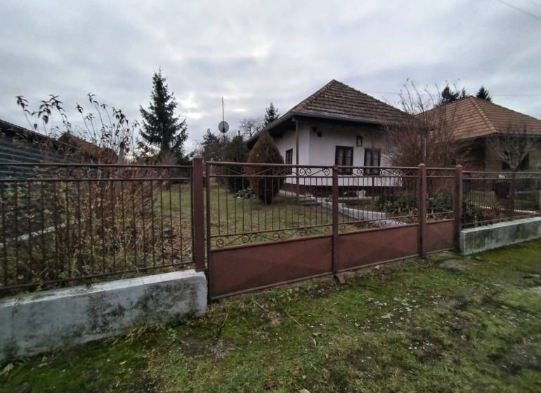 A family house in Dolný Pial surrounded by a garden and a fence, overcast weather.