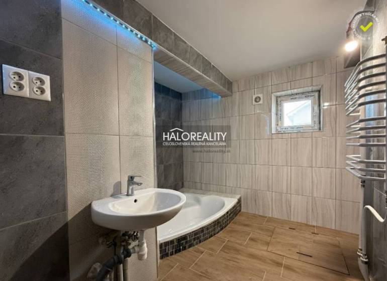 A family house bathroom with a bathtub, a sink, and a wooden decor floor.