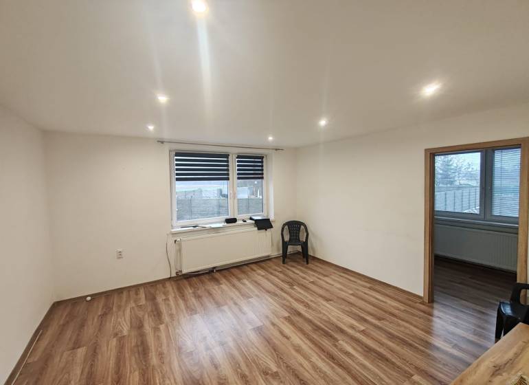 A room with a wooden decor floor and a plastic chair in a 3-room apartment.