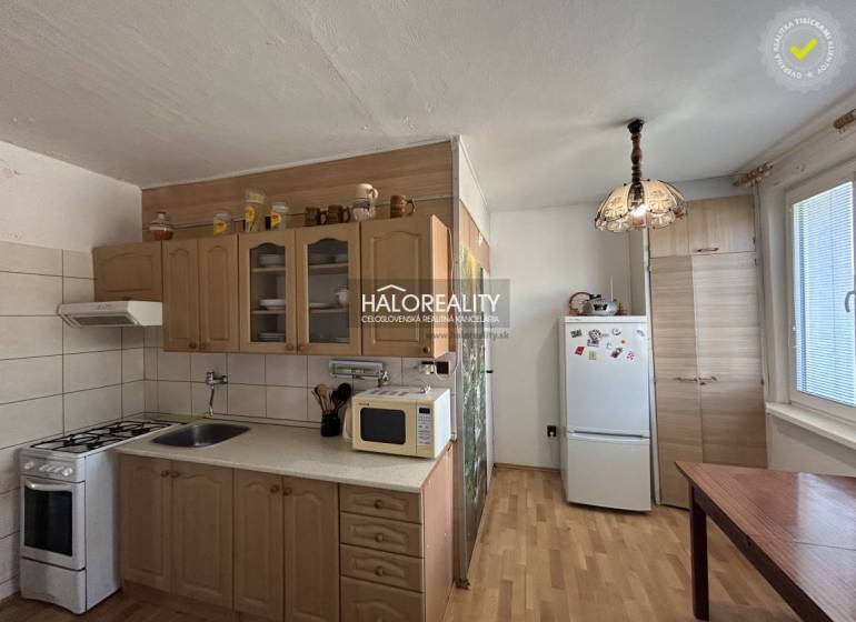 A kitchen in a 2-room apartment with a kitchen unit, refrigerator, and floor with a wooden decor.