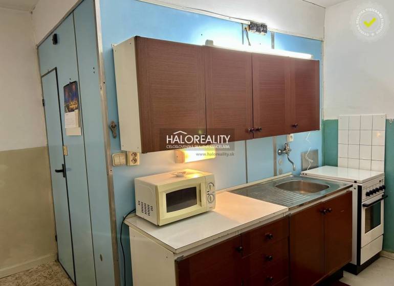 A kitchen with older cabinets, a microwave, and a stove in a 4-room apartment.