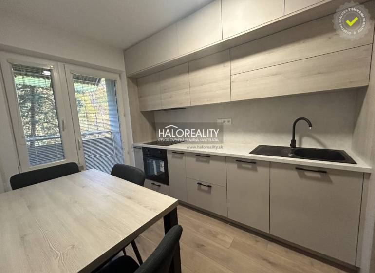 Kitchen in a three-room apartment with a wooden decor floor and a dining table.