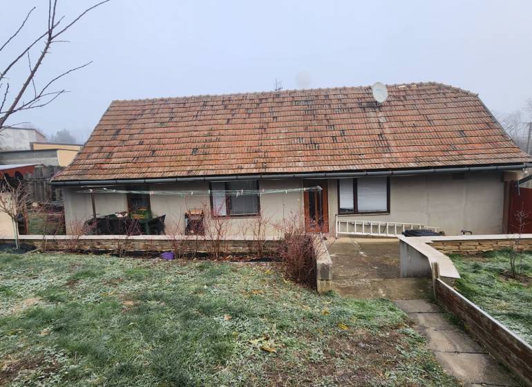 A family house in Brestovany with a traditional roof and a landscaped garden during autumn.