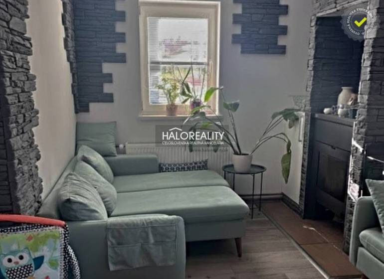 Living room with a green sofa, fireplace, and decorative stone, 4-room apartment.