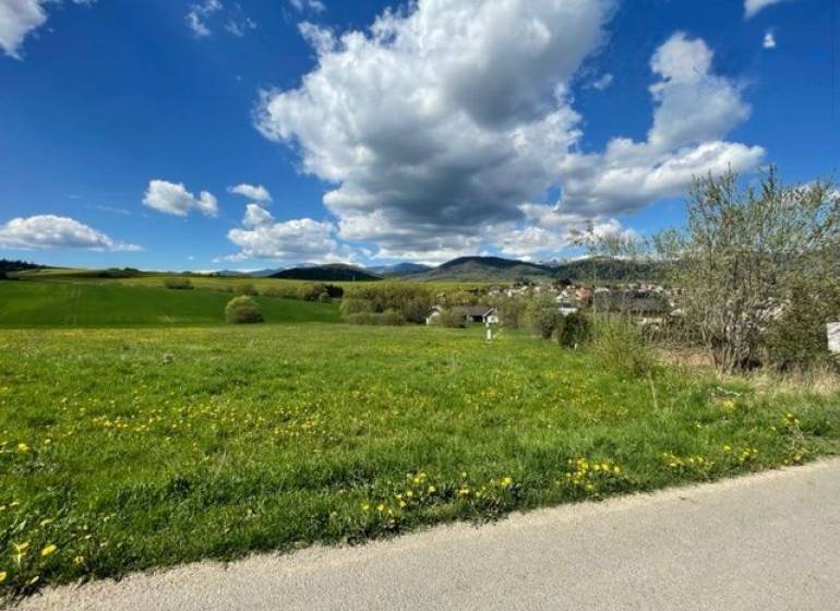 Beautiful green residential plots in Kotrčiná Lúčka under a blue sky with clouds.