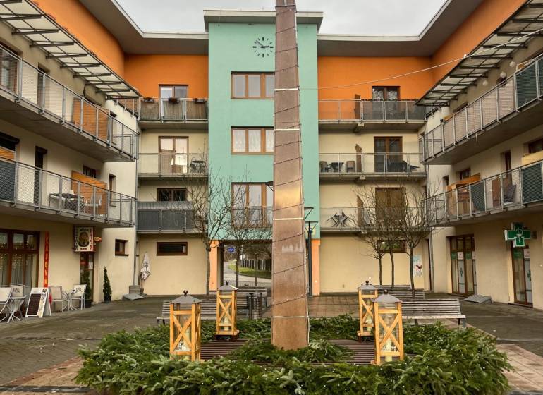 The courtyard in Oščadnica with a decorative column and modern apartments around.