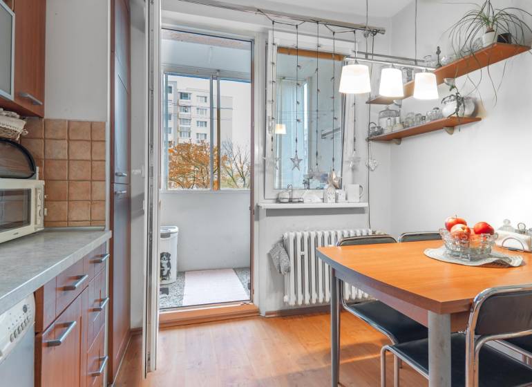 Kitchen with dining table, wood-patterned floor, access to balcony, 4-room apartment.