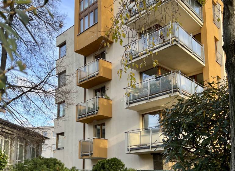 A building with balconies surrounded by trees and shrubs on Fazuľová Street in Bratislava - Old Town.
